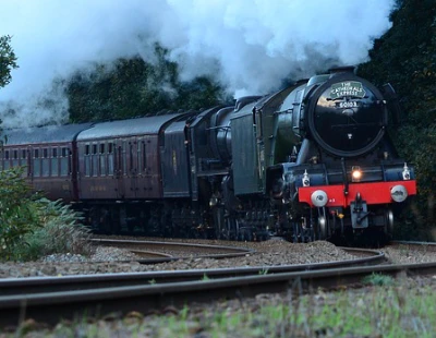 The flying Scotsman train steaming round a bend in open countryside.